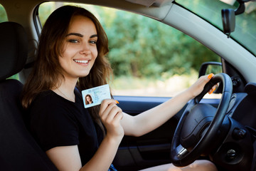 Student in a modern car showing driving licence - obrazy, fototapety, plakaty