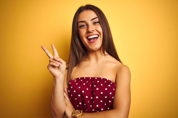 Young beautiful woman wearing red t-shirt standing over isolated yellow background smiling with...