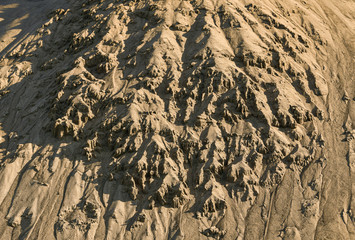 crumbling sand from the slope of a sandy hill.