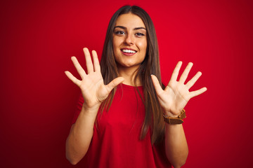 Young beautiful woman wearing t-shirt standing over isolated red background showing and pointing up...