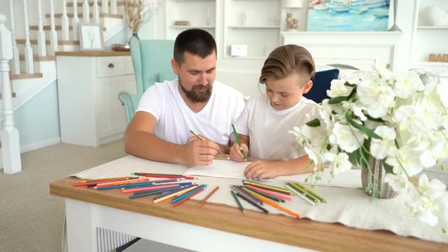 cheerful child painting with color pencils at home with dad