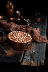 homemade tiramisu in oval copper pan on rustic wooden table