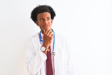 Young african american doctor man wearing sthetoscope over isolated white background with hand on chin thinking about question, pensive expression. Smiling with thoughtful face. Doubt concept.
