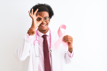 Young african american doctor man holding cancer ribbon over isolated white background with happy face smiling doing ok sign with hand on eye looking through fingers