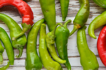 Bitter red and green peppers on a white wooden background.