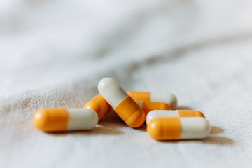 Close up of colorful medical capsules on white sheet.