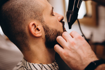 Work in the Barber shop. Barber shaving a bearded man in a barber shop, close-up. Master cuts hair and beard