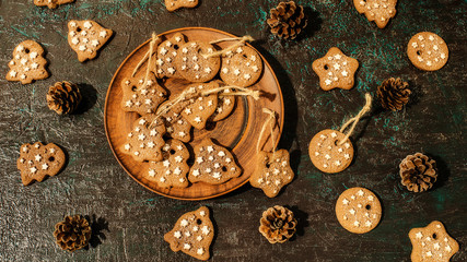 Christmas theme with cookies, spruce cones on a dark background. Flat lay.