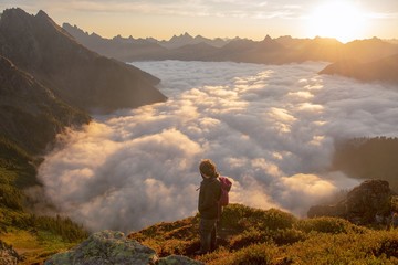 A woman standing above the clouds watching the sun rise 