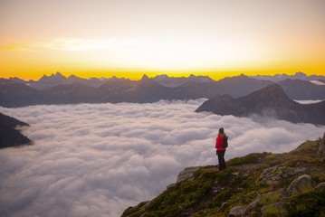A woman standing above the clouds watching the sun rise 