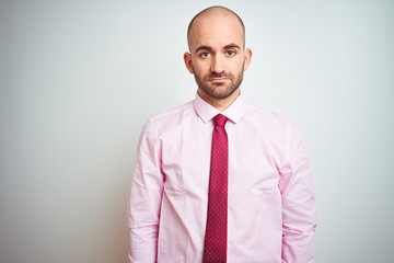 Young business man wearing pink tie over isolated background with serious expression on face. Simple and natural looking at the camera.