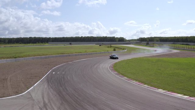 Japanese car drifting on turn at racing track. Aerial view car drifting with smoke from burning tires on speed track. Sportsman driving on racing car on asphalt track