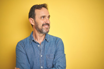 Fototapeta premium Handsome middle age senior man with grey hair over isolated yellow background smiling looking to the side and staring away thinking.
