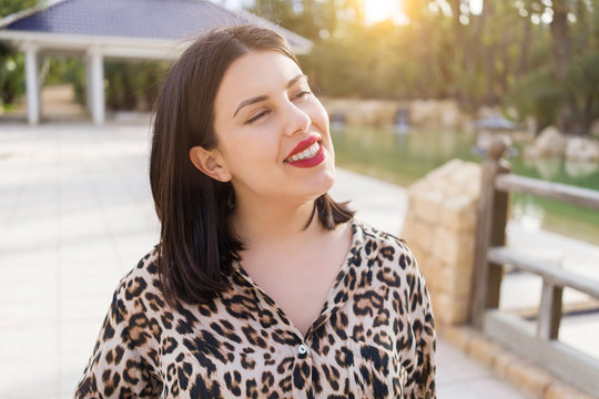 Young beautiful woman with red lips smiling happy at garden