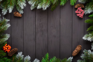 Christmas or New Year decoration background: fir-tree branches, colorful balls, candy cane on black background. Top view with copy space. Falt lay.