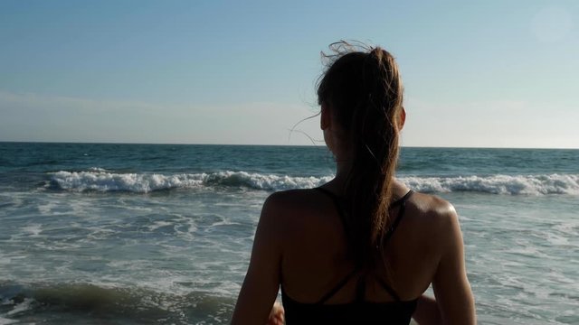 Athletic woman at the beach relaxing and enjoying the view after her workout