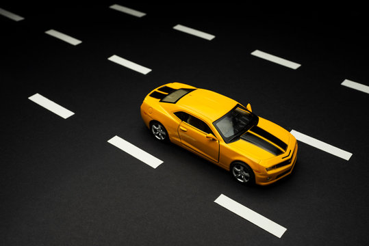 Yellow Toy Sports Car With Two Doors On A Black Background.