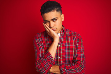 Young brazilian man wearing shirt standing over isolated red background thinking looking tired and bored with depression problems with crossed arms.