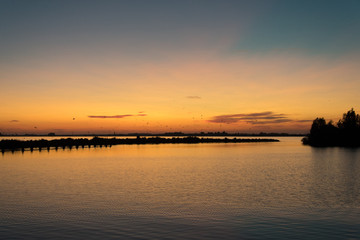 Fototapeta na wymiar Birds in sunset above lake in Friesland, The Netherlands. Typical Dutch landscape and scene.