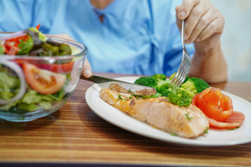 Asian senior or elderly old lady woman patient eating breakfast healthy food with hope and happy while sitting and hungry on bed in hospital.