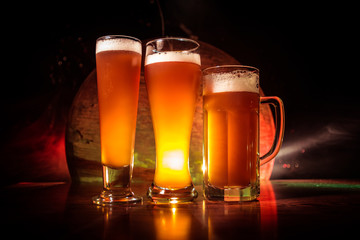 Creative concept. Beer glasses on wooden table at dark toned foggy background.