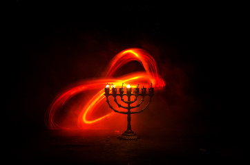 Fototapeta na wymiar Low key image of jewish holiday Hanukkah background with menorah on dark toned foggy background