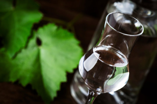Grape vodka, pisco - traditional Peruvian strong alcoholic drink in elegant shot glasses on vintage wooden table, copy space