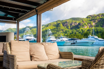 Resting corner with view of Luxury yachts and Boats in sunny summer day at marina of Eden Island, Mahe, Seychelles