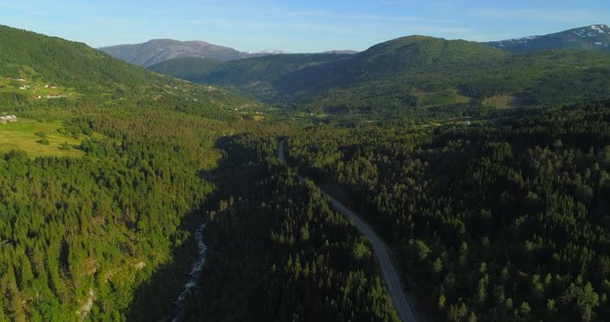 Aerial: Drone approaching motor home moving on country road amidst green trees in forest - Borgund, Norway