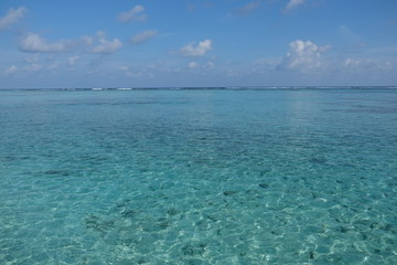 Fototapeta na wymiar wide green sea horizon under white cloudy sunny blue sky in Maldives.
