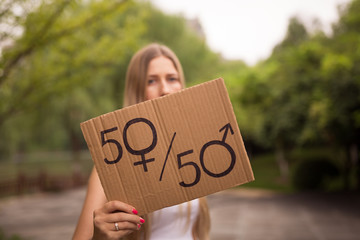 Gender equality concept as woman hands holding a paper sheet with male and female symbol over a...