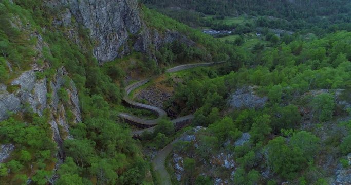 Aerial: Drone approaching empty winding road surrounded trees - Borgund, Norway
