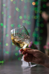 Hand sommelier holding glass of white wine. Swirling wine glass in wine tastings  White wine concept. Wine tour. Vertical, cold toning. Free space for text.