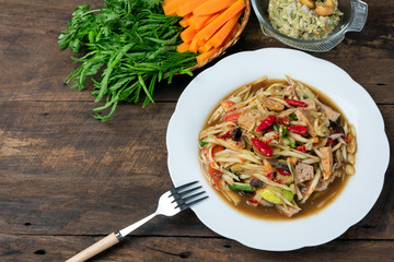 green papaya salad with pork  in white plate on wood background