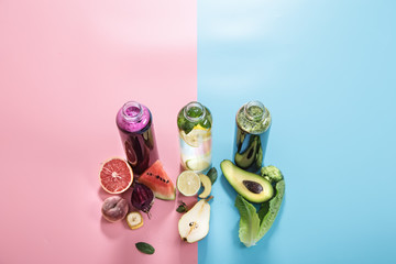 Glass bottles with natural drinks on a colored background