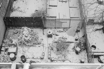 Black & White bird's eye view of an old chaotic looking backyard during a heavy snowstorm in Harlem, New York, USA