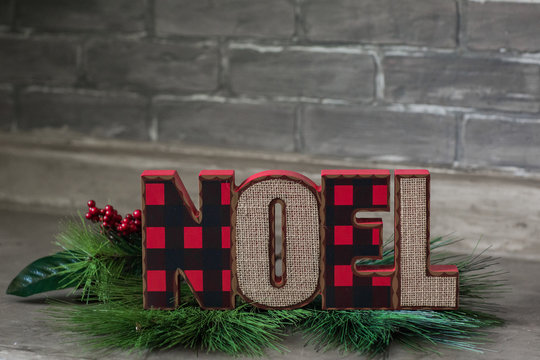 Isolated Words Noel With Green Holly  On Gray Brick Background