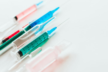  syringes and ampoules with multicolored liquid on a white background.