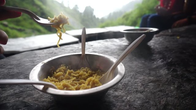 Steaming hot ramen noodles in a steel bowl served at a small restaurant on triund bhagsu falls trek in the himalayas
