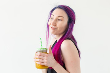 Cute young mixed race hipster girl with colored hair drinks fruit smoothie before starting a yoga class on a white background. Healthy lifestyle concept. Copyspase.