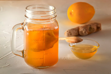 Homemade fermented drink Kombucha in glass jar with lemon, honey and ginger on a wooden table. Close-up