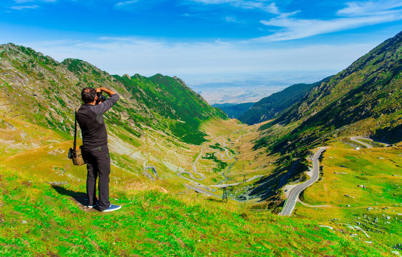 photographer man taking photos in nature mountain landscape. Fagaras, Romania