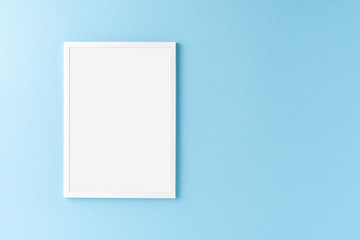 White photo frame with copyspace on blue background. Home decoration