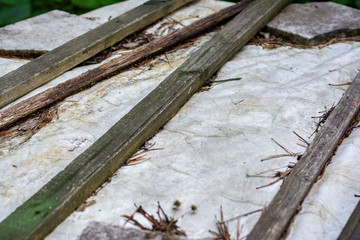 Part of the roof in an abandoned house in the forest casually covered with boards and cloth and sprinkled with fir needles