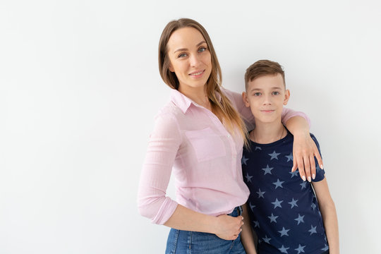Good-looking single-parent mom and teen son on white background. Cohesion, friendship and family relations.