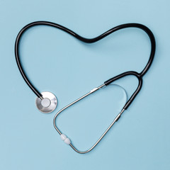 Stethoscope in shape of heart on blue table background, Good health from Doctor concept, Top view...