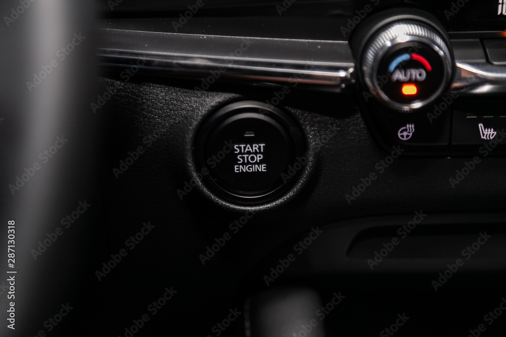 Wall mural Car engine push start stop button ignition remote starter. Car dashboard:  black engine start stop button, car interior details. Soft focus