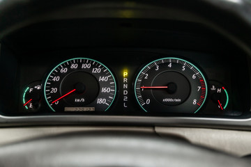 close-up of round dashboard, speedometer and tachometer with white backlight. modern car interior.