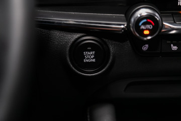 Fototapeta na wymiar Car engine push start stop button ignition remote starter. Car dashboard: black engine start stop button, car interior details. Soft focus