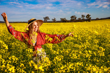 Fototapeta premium Smiling Young Woman in Flowering Canola Field in Western Australia